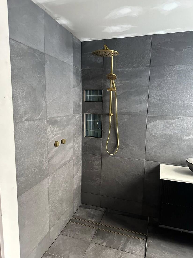 Slate-tiled wet room with brushed brass rain shower, hand shower and double recessed niche